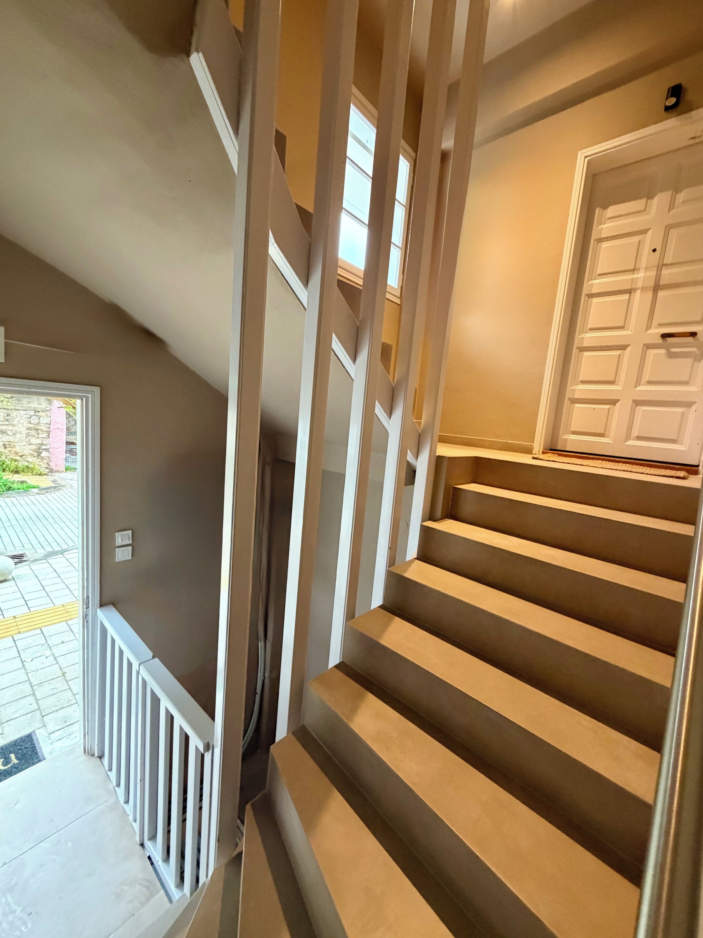 A staircase with a handrail, a door, and a window.