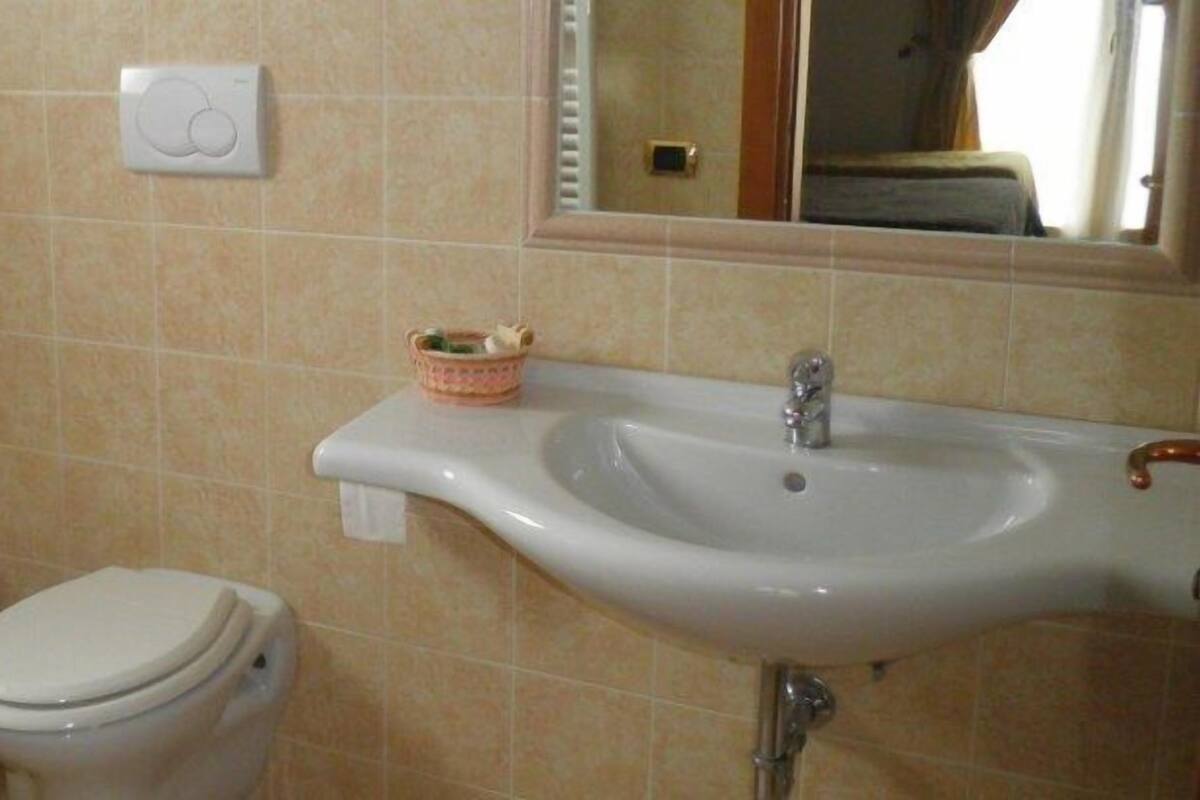 Een badkamer met een bidet, toilet, wastafel en een spiegel.
