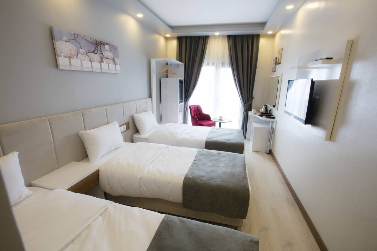 A hotel room with two beds, a TV, a small table, and a red chair.