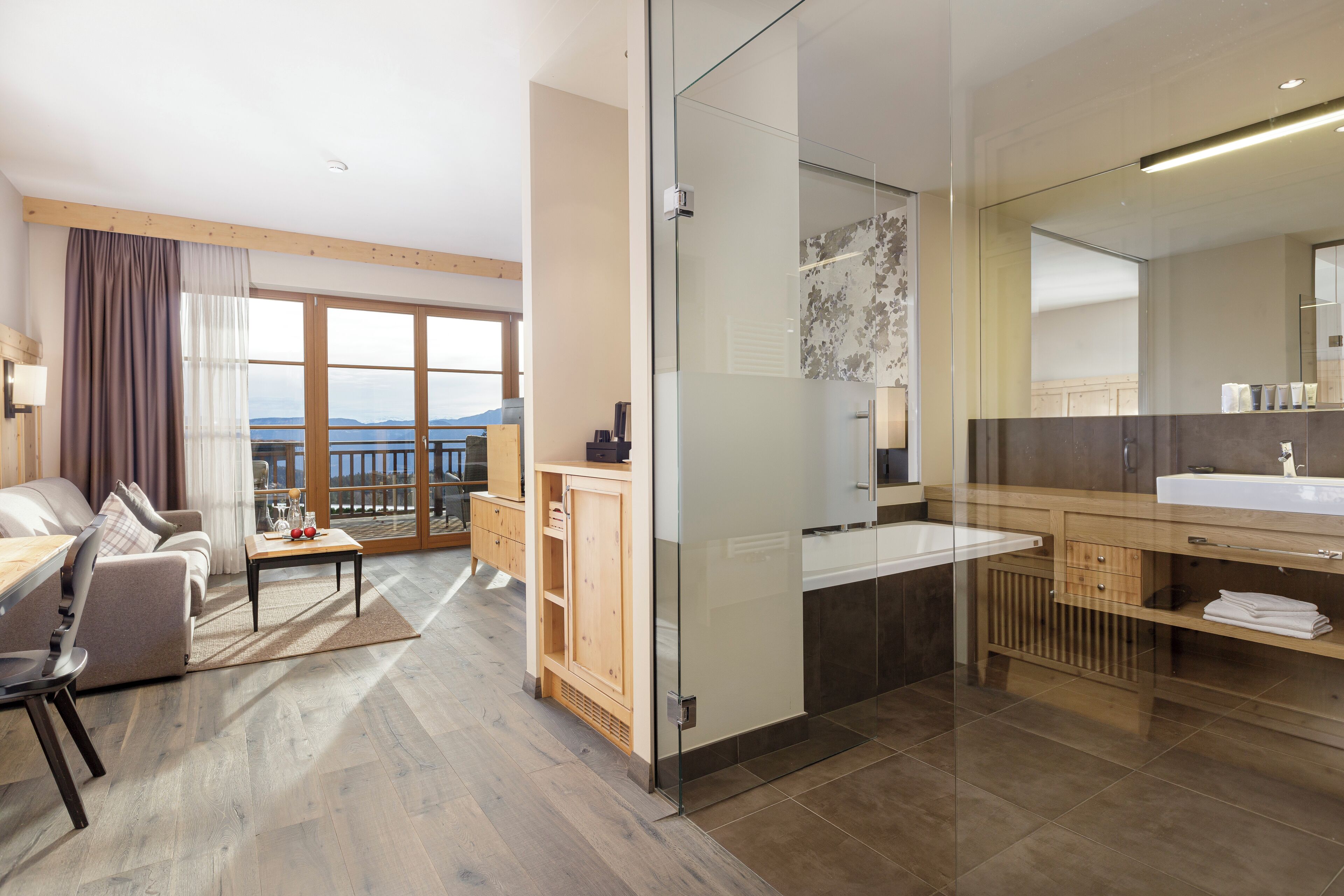 A modern hotel room with a balcony, a glass shower enclosure, and a wooden vanity.