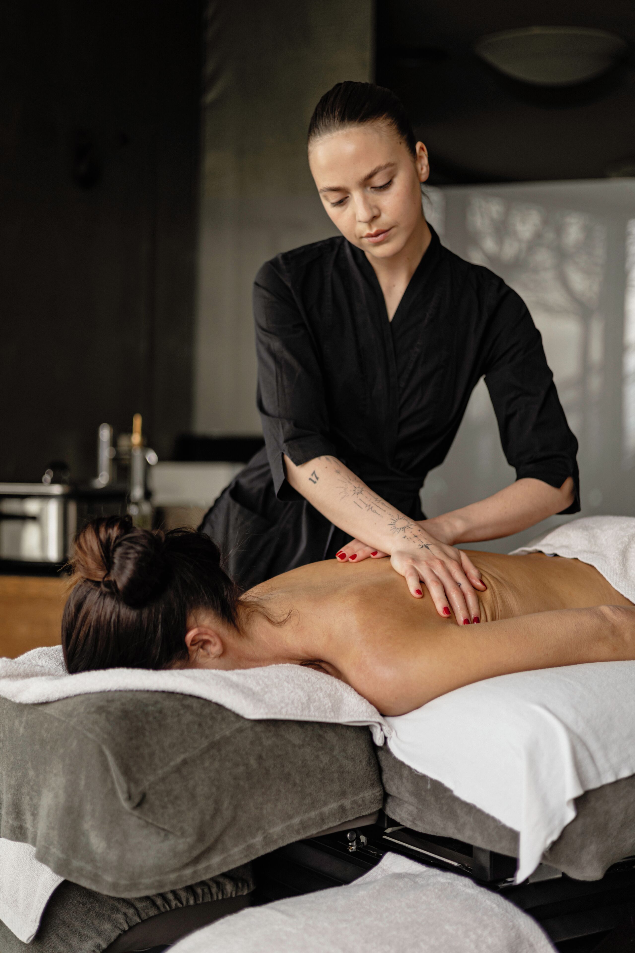 Una seduta di massoterapia in una spa, con lettino da massaggio, asciugamani e un terapista di massaggio.