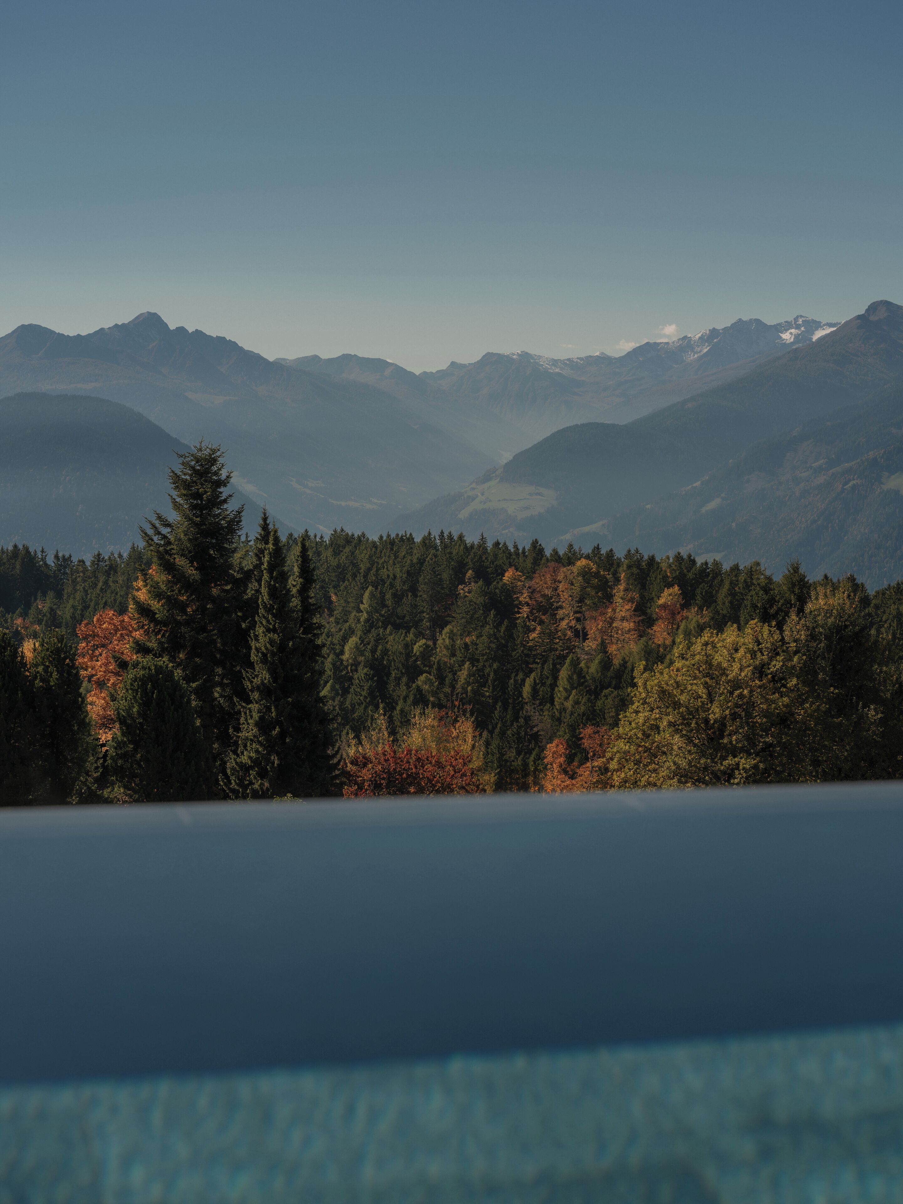 A mountainous landscape with a forested area and a lake in the foreground.
