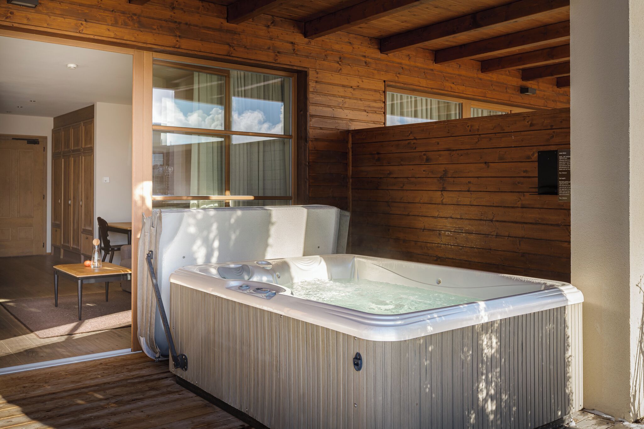 Ein Whirlpool in einer Holzhütte mit Blick zum Himmel durch ein Fenster.