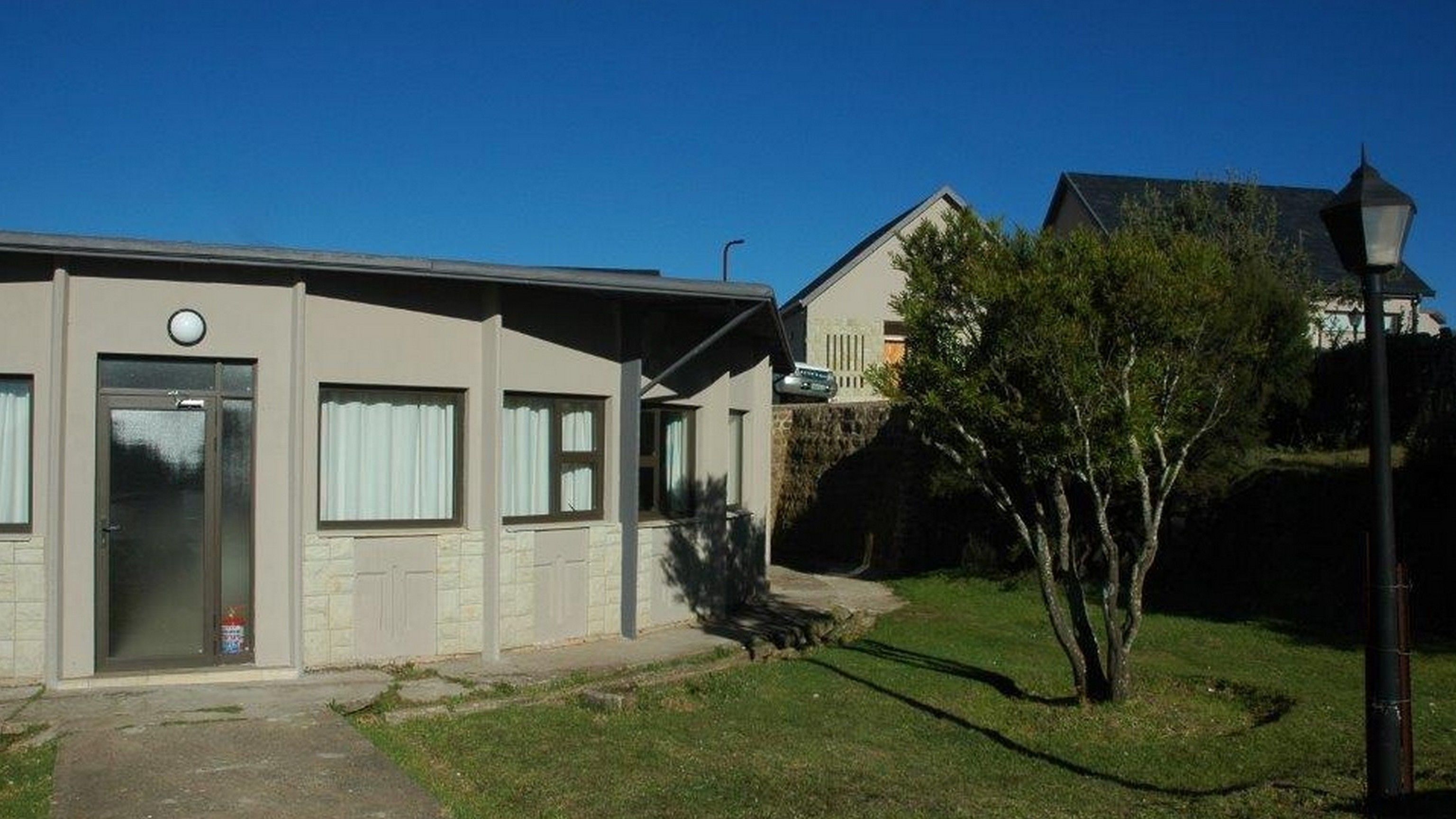 A two-story building with a flat roof, a front door, and windows.