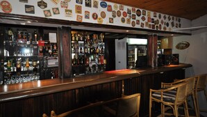 A bar with a wooden counter, various bottles, and a wall decorated with beer labels. - Witsieshoek Mountain Lodge (Maluti a Phofung)