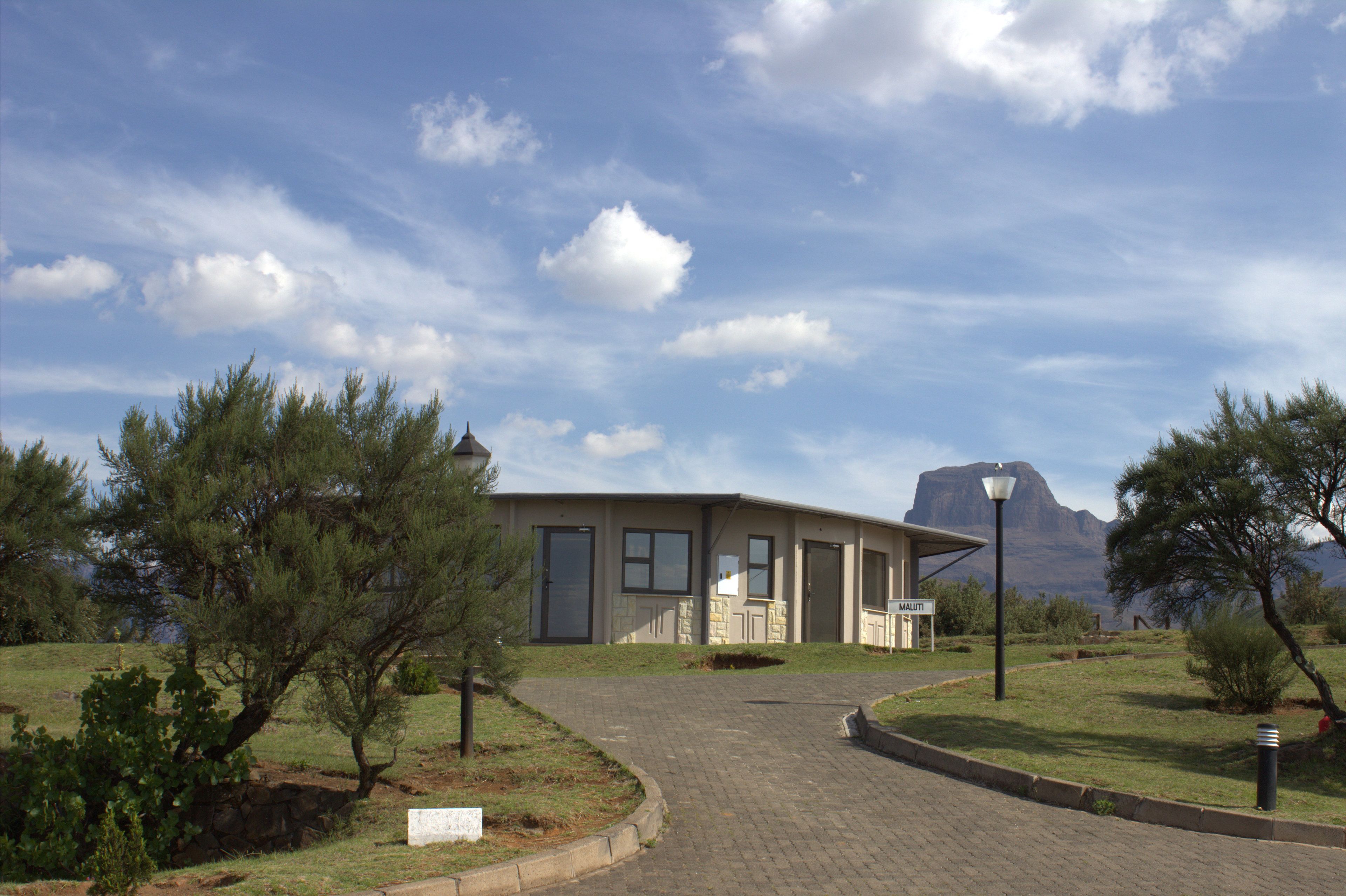 A building with a paved driveway, a covered porch, and a mountain in the background.