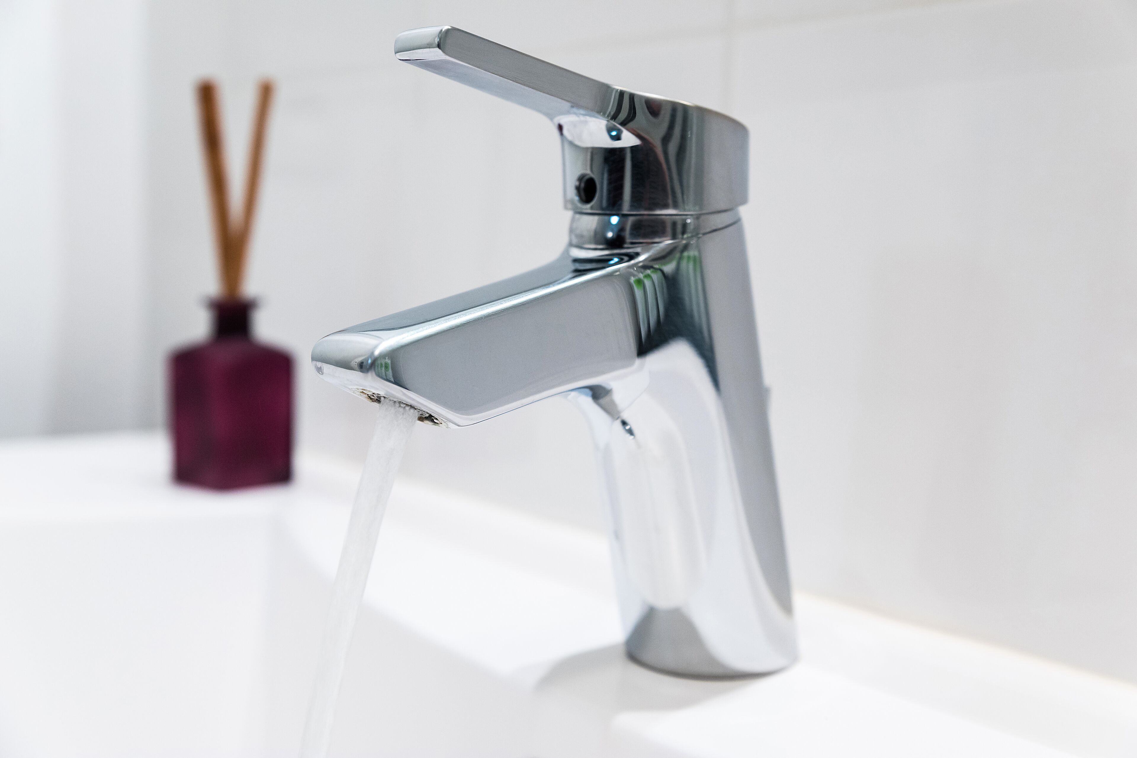 A modern chrome faucet with a single lever handle, mounted on a white countertop.