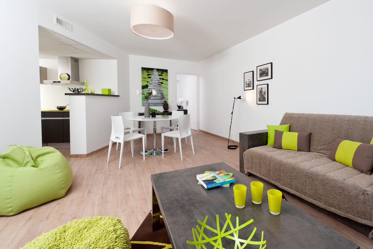A modern living room with a sofa, a coffee table, and a dining area with chairs.