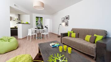 A modern living room with a sofa, a coffee table, and a dining area with chairs.