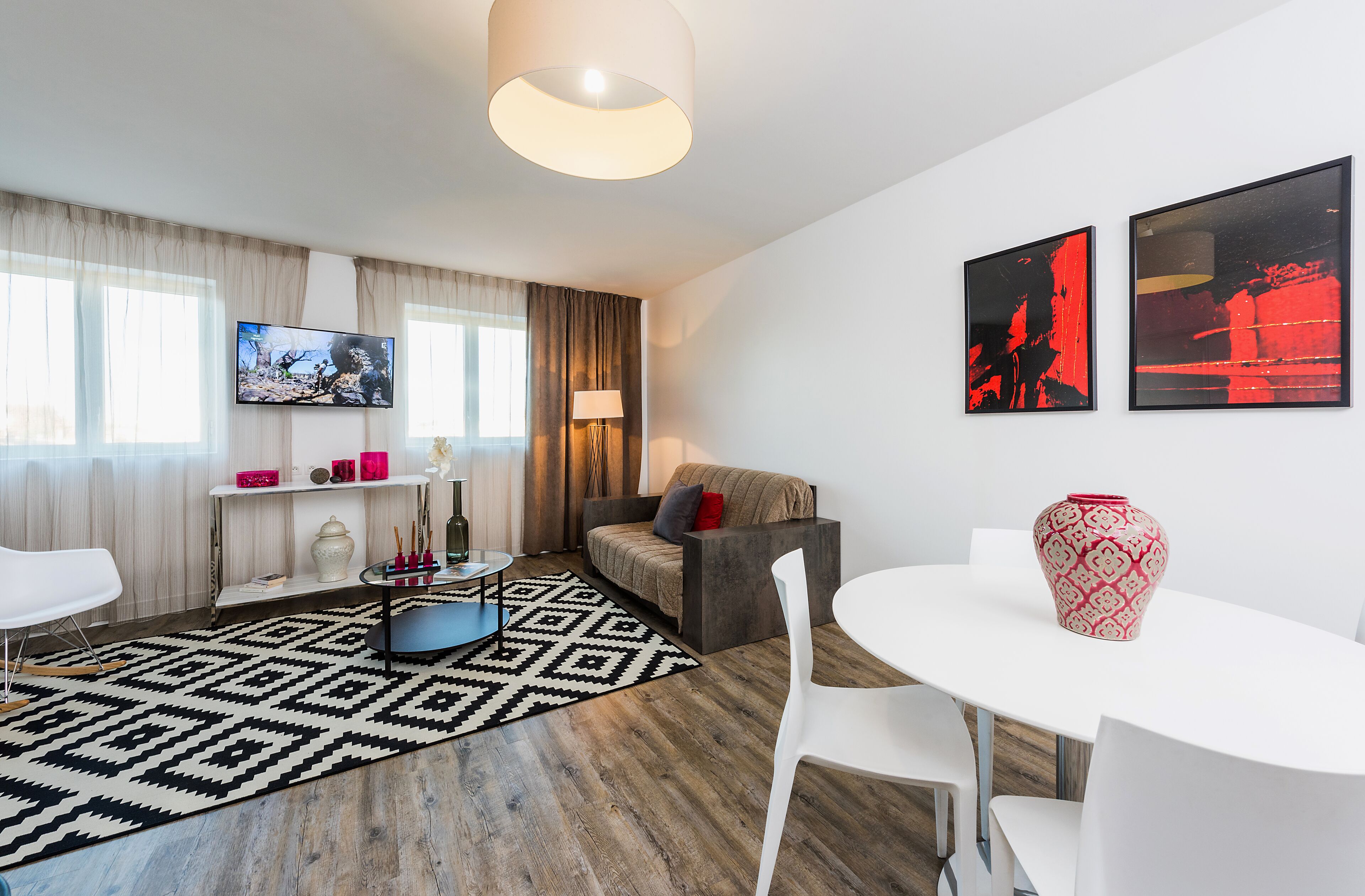 A modern living room with a sofa, a TV, a coffee table, and a dining area.