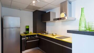 Una cucina moderna con frigorifero in acciaio inox, forno integrato e piano di lavoro giallo.