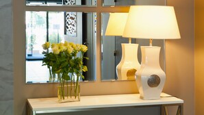 Een bijzettafeltje met een vaas gele bloemen, een witte lamp en een decoratieve vaas.