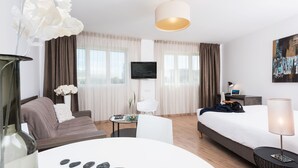 Een moderne hotelkamer met een bed, een bank, een eettafel en een televisie.