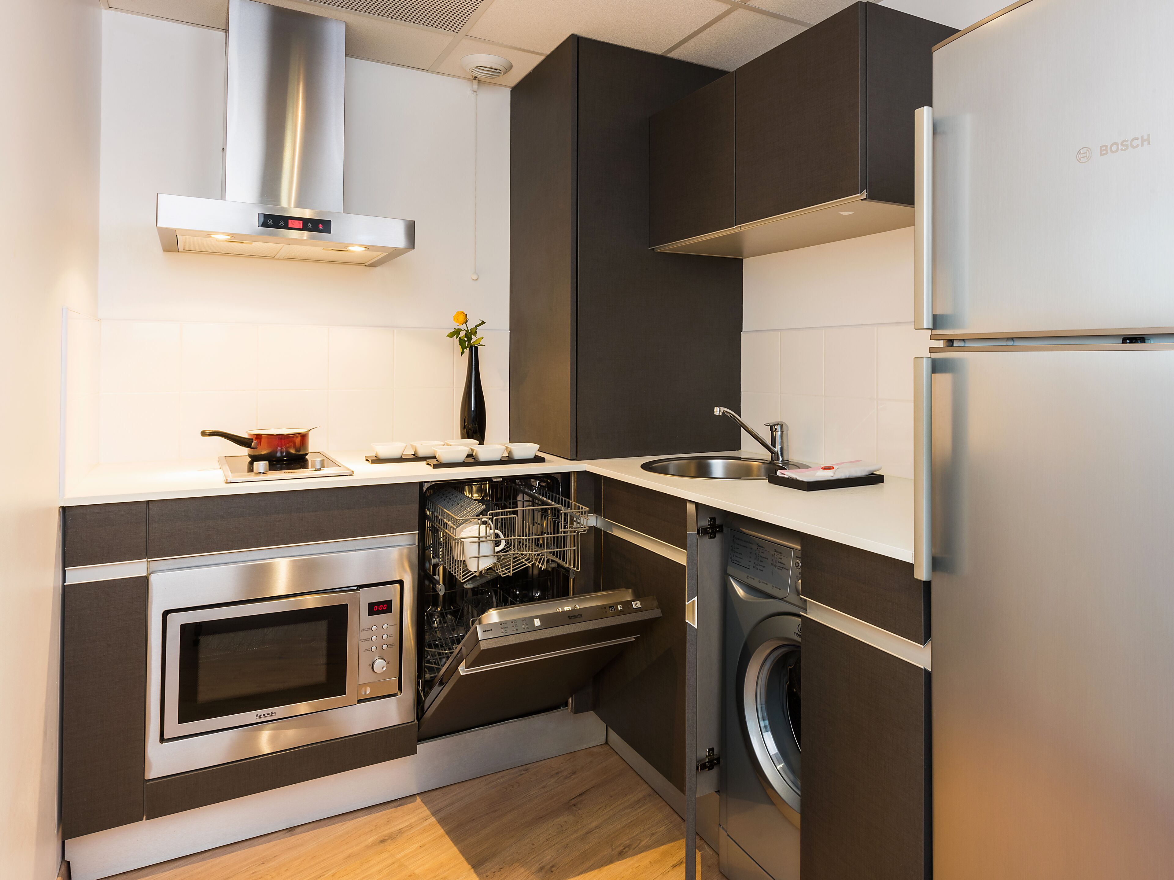 A compact kitchen with a built-in oven, microwave, dishwasher, and washing machine.