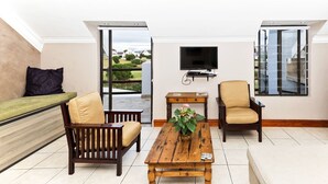 Un salon moderne comprenant un canapé, deux fauteuils, une table basse et un téléviseur.