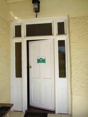 Una puerta blanca con un letrero que dice "bakone" encima, flanqueada por dos ventanas.