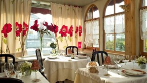 A dining area with tables set for a meal, large windows with curtains, and a view of greenery outside. - Hotel Restaurant Robichon (Loray)