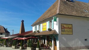 A building with a sign for 'Robichon' and outdoor seating with umbrellas. - Hotel Restaurant Robichon (Loray)