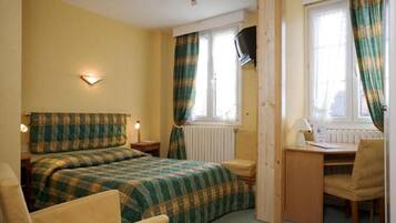 A room with two beds, a desk, and a chair.