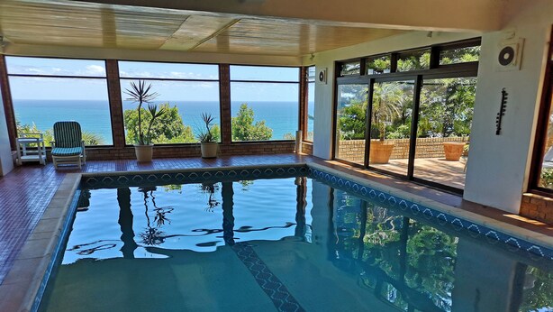 An indoor swimming pool with clear views of the ocean through large windows. - Magic Camps Bay (Cape Town)