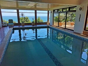 An indoor swimming pool with clear views of the ocean through large windows. - Magic Camps Bay (Cape Town)