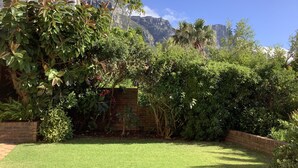 A well-maintained garden with a variety of shrubs and a neatly trimmed lawn, set against a backdrop of rocky mountains. - Magic Camps Bay (Cape Town)