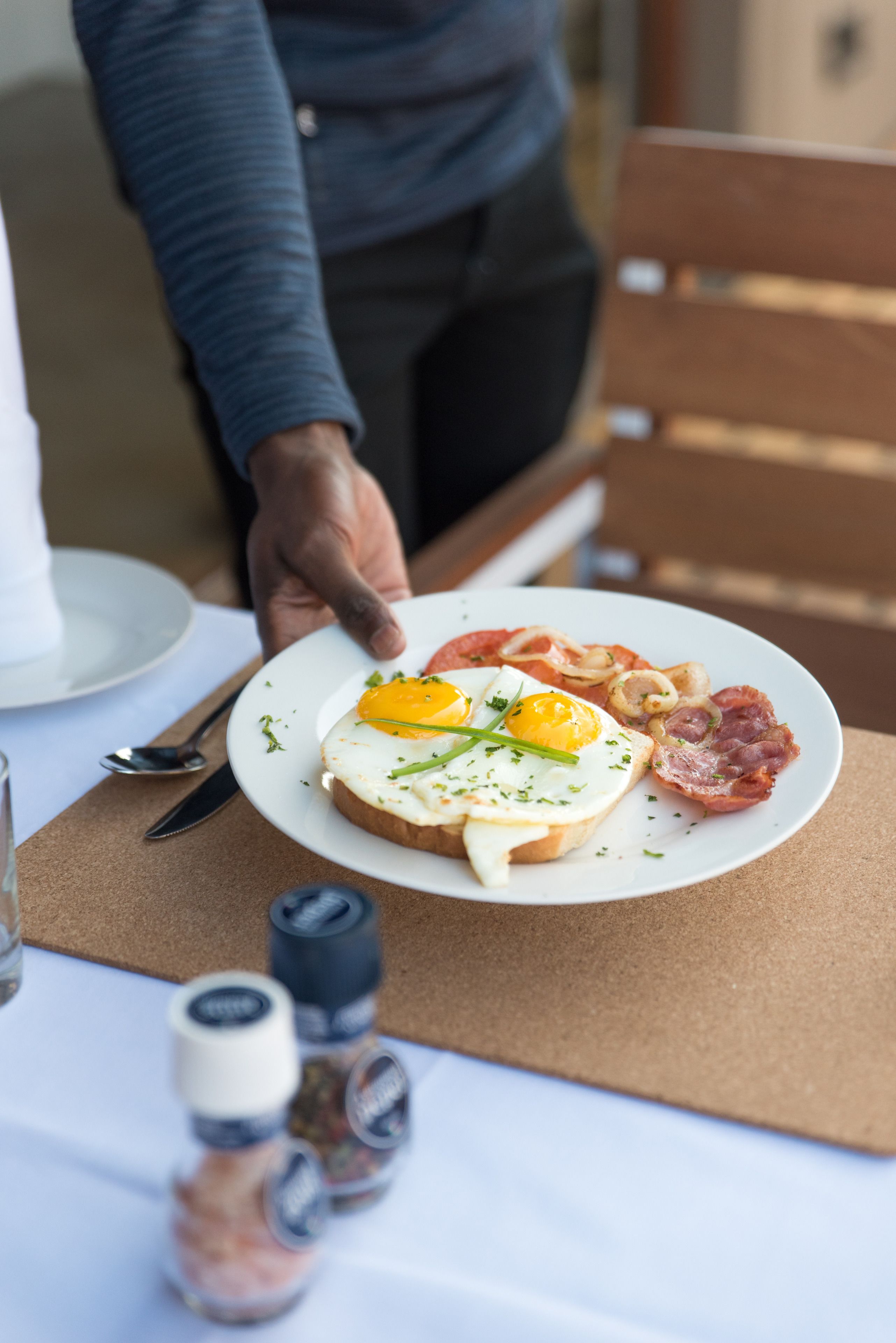 A plate with eggs, bacon, and onions on a table.