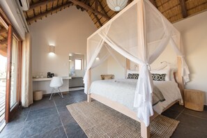 Un dormitorio con cama con dosel, un escritorio y una silla.