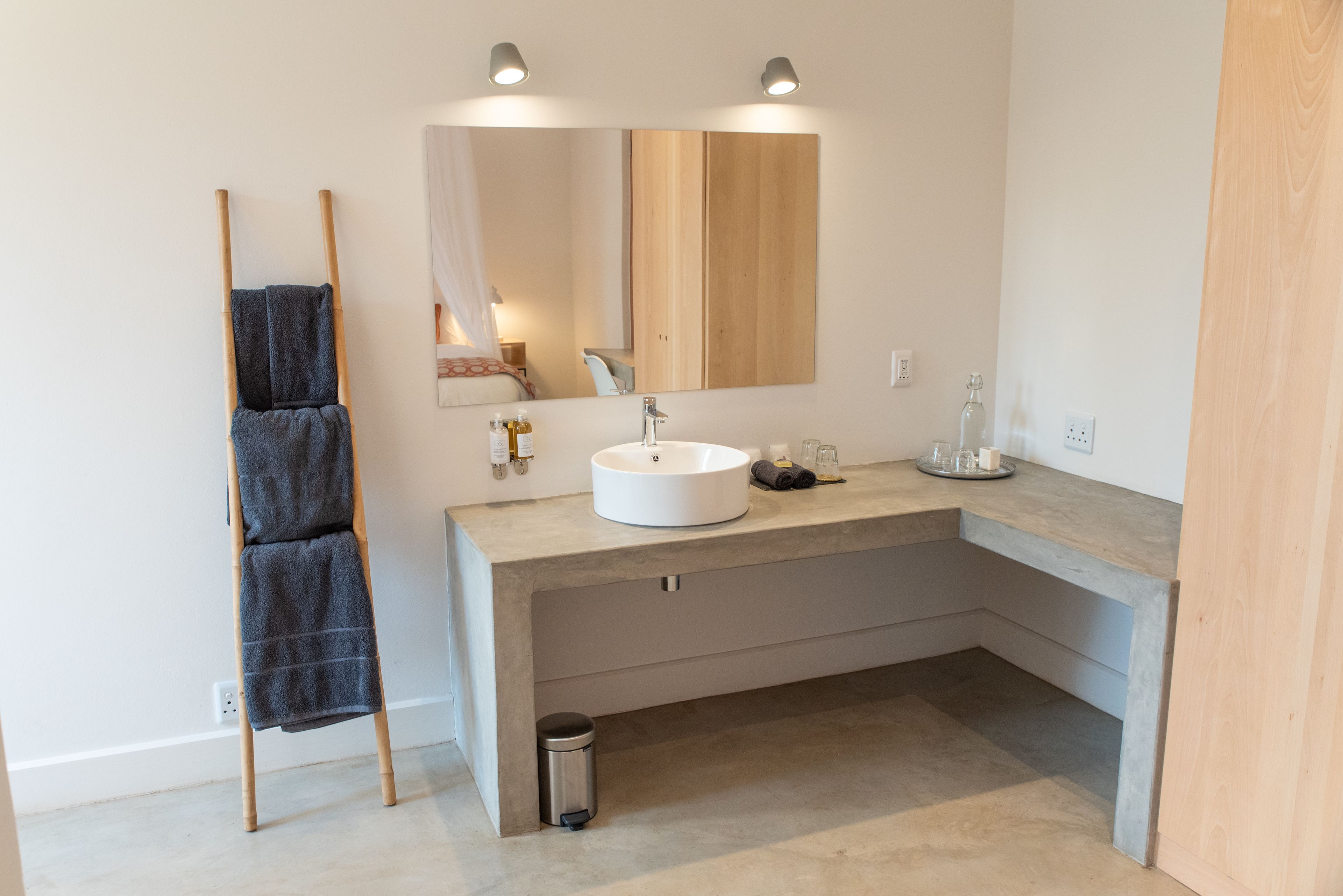 A modern bathroom with a wooden vanity, a large mirror, and a towel rack.