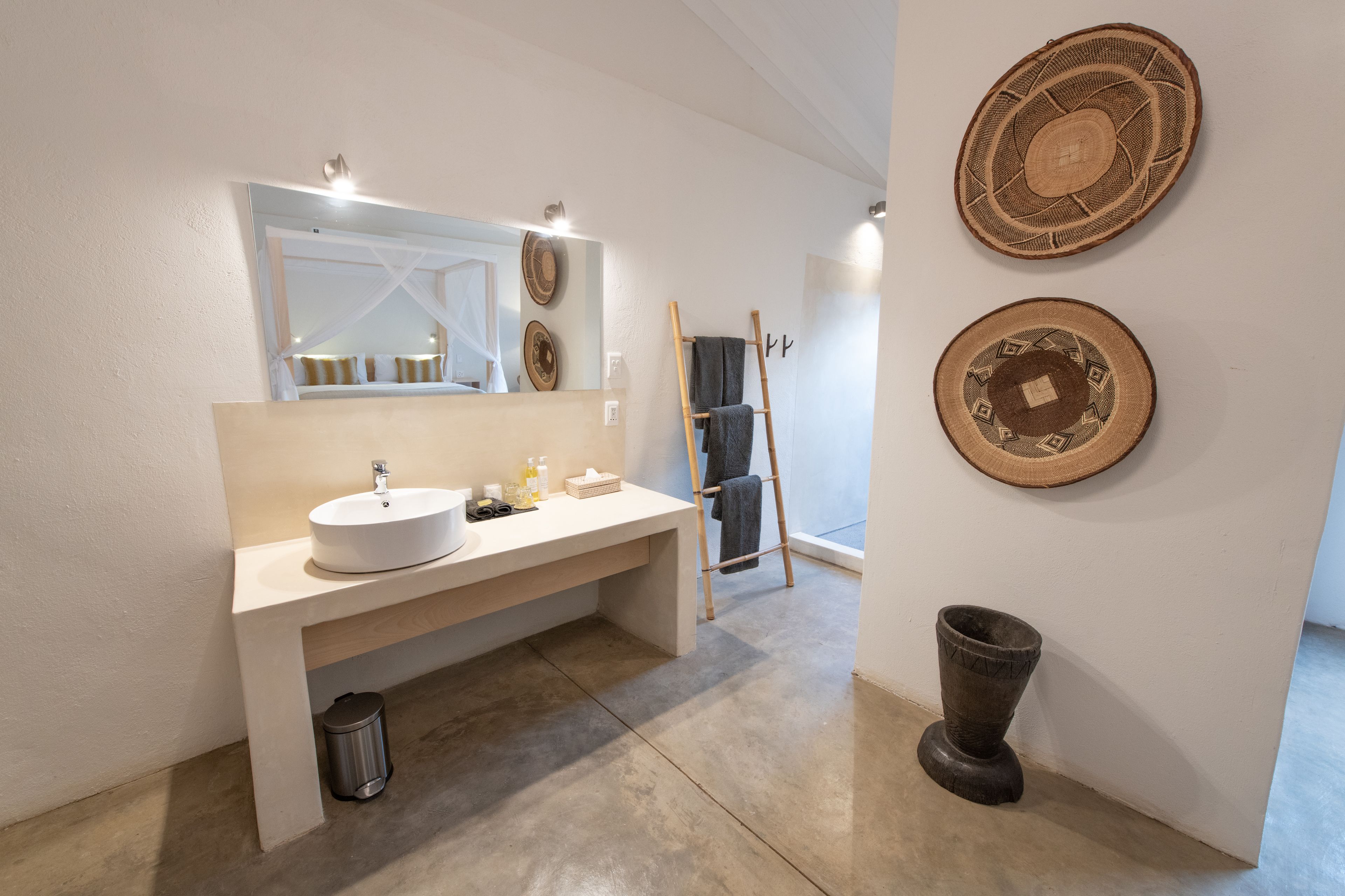 Un baño moderno con un espejo grande, un lavabo y dos cestas decorativas tejidas en la pared.