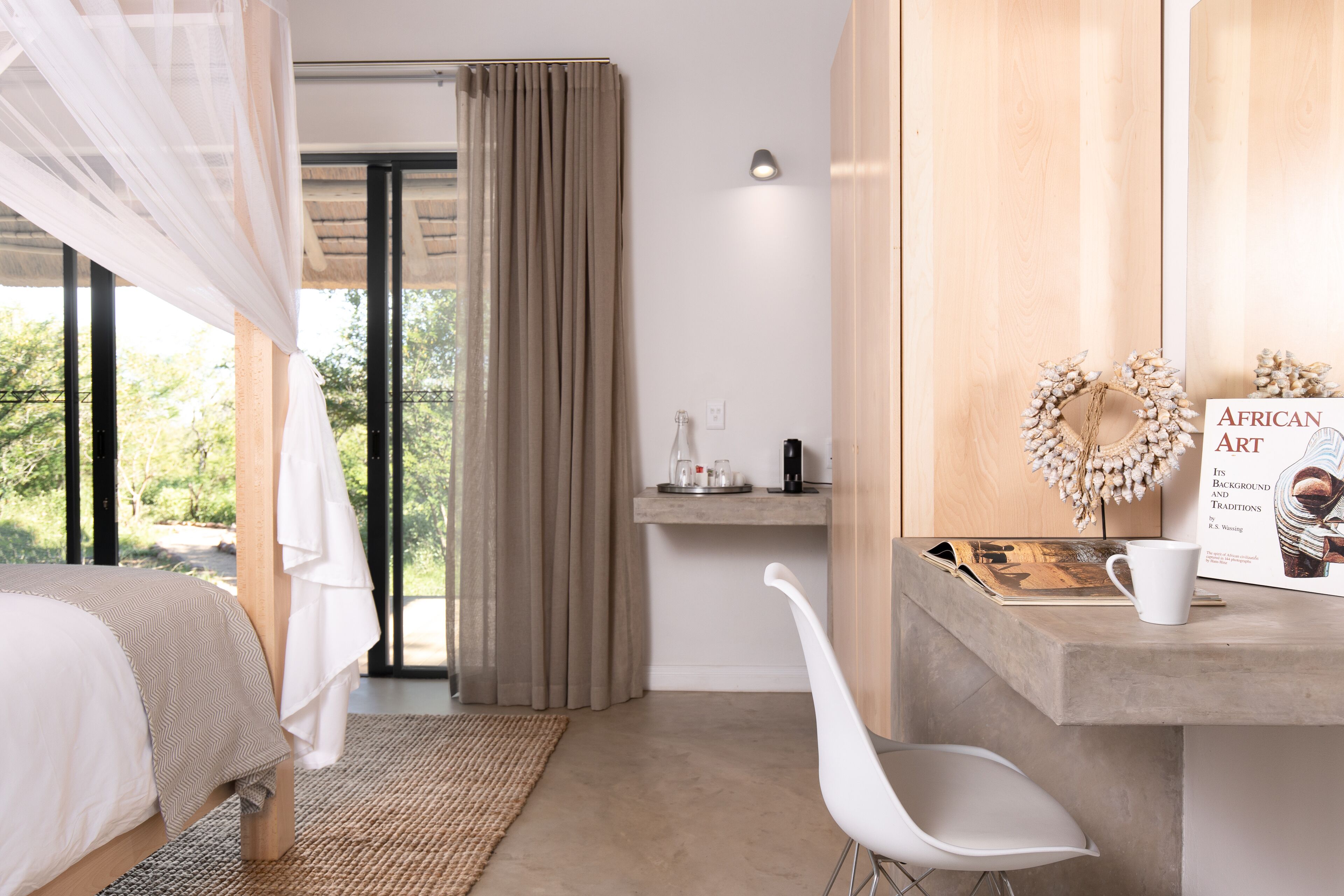 A bedroom with a bed, a desk, a chair, a nightstand, and a window with curtains.