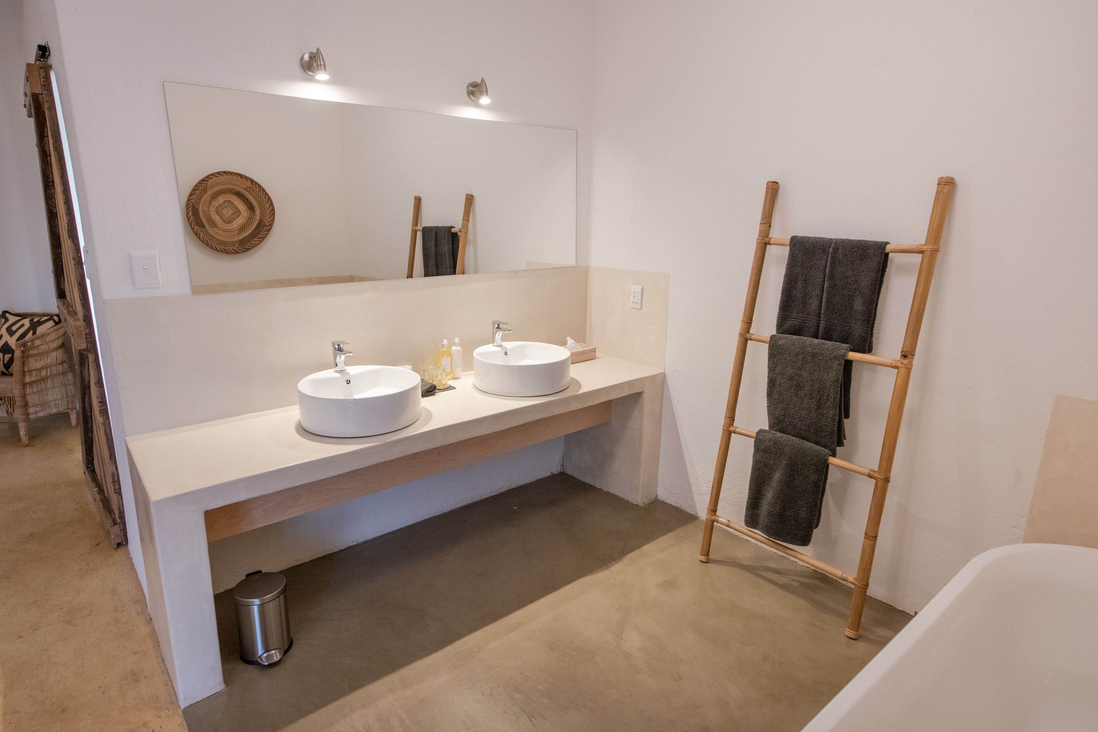 Un baño moderno con dos lavamanos, un espejo grande y un perchero de madera.