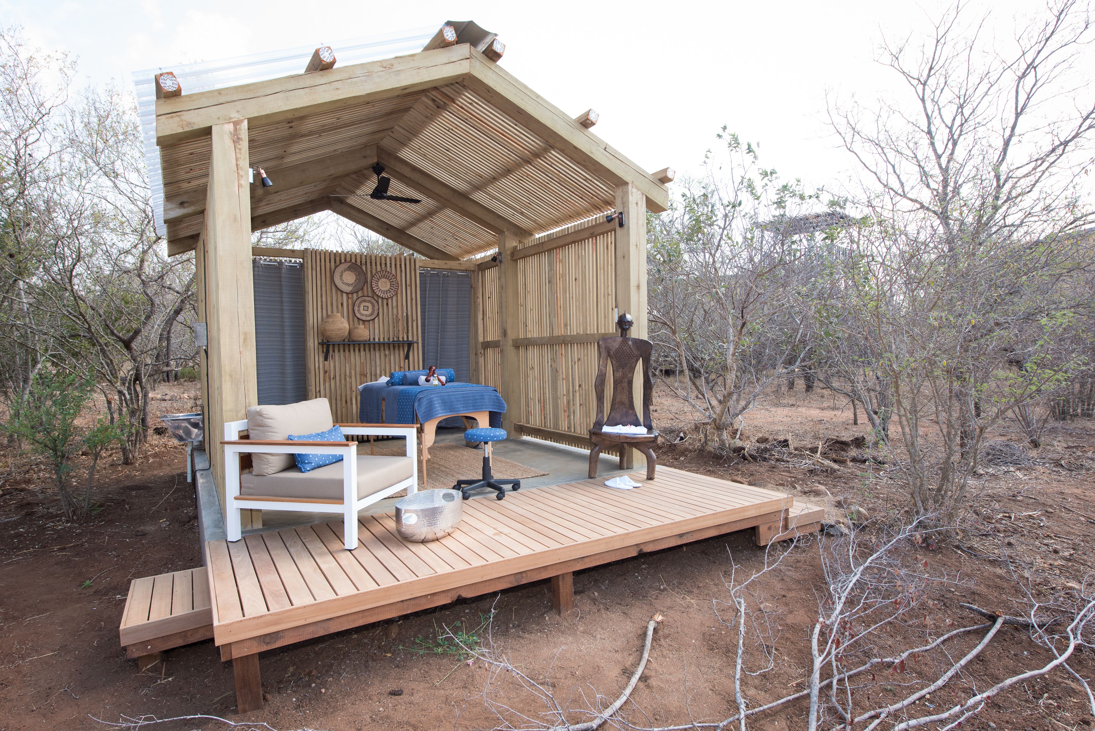 Una terraza de madera con un sofá, una mesita y una silla.