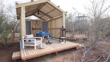 A wooden deck with a sofa, a small table, and a chair.