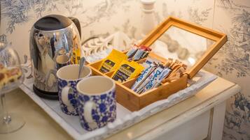 Un tavolo con una caffettiera, due tazze bianche e azzurre decorate, un vassoio con una scatola di legno contenente diversi oggetti e una cornice con un'immagine.