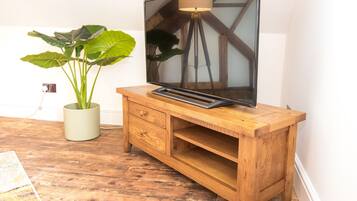 Un mueble bajo de madera para televisor con un televisor de pantalla plana, una planta en maceta y suelo de madera.