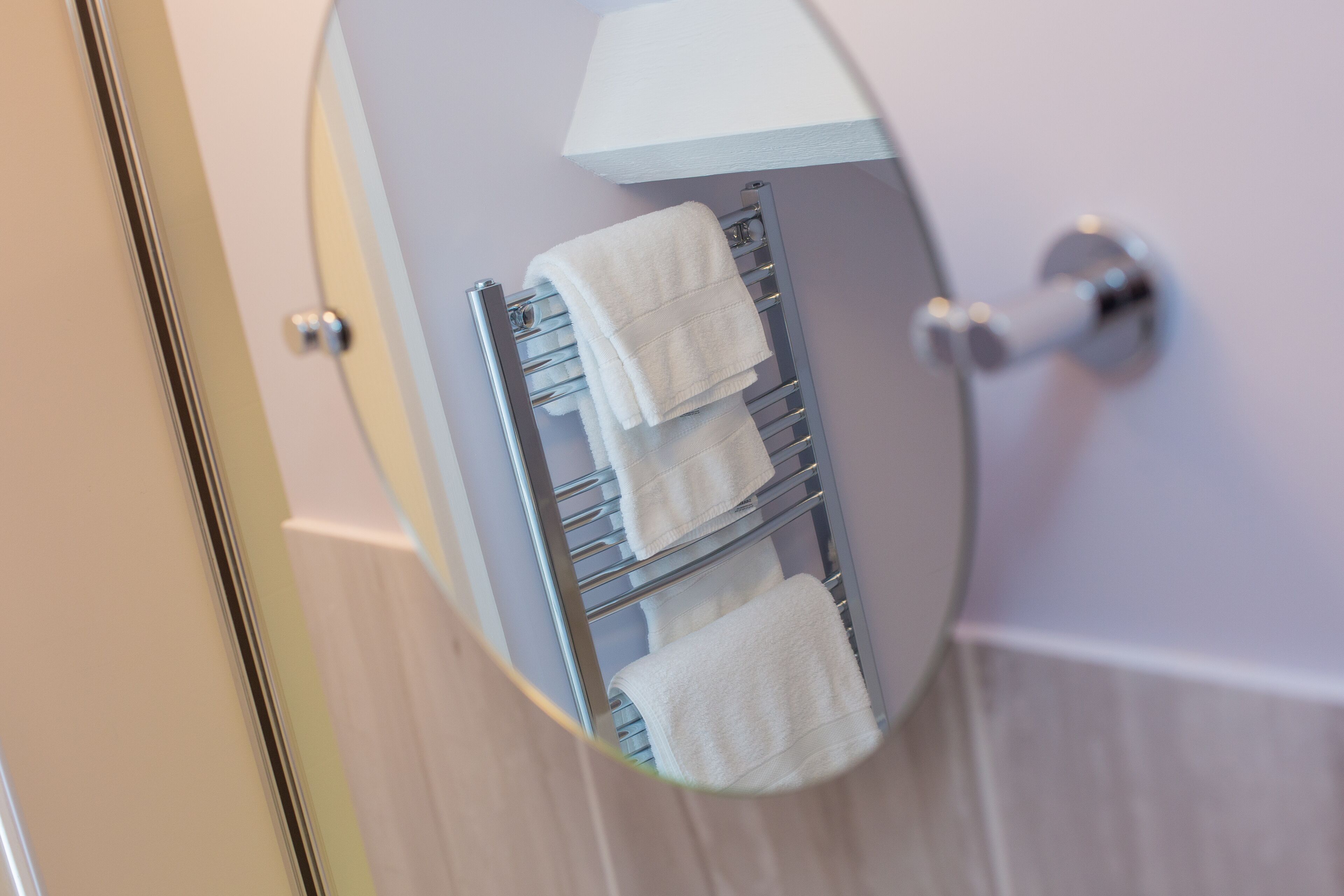 Ein Badezimmer mit Handtuchhalter und mehreren weißen Handtüchern.