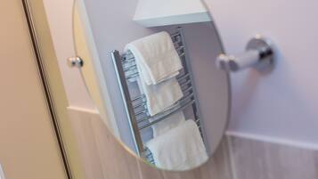 Ein Badezimmer mit Handtuchhalter und mehreren weißen Handtüchern.