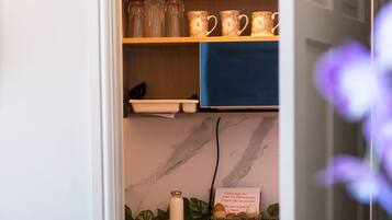 A kitchen with a marble countertop, a coffee machine, and a basket of eggs.