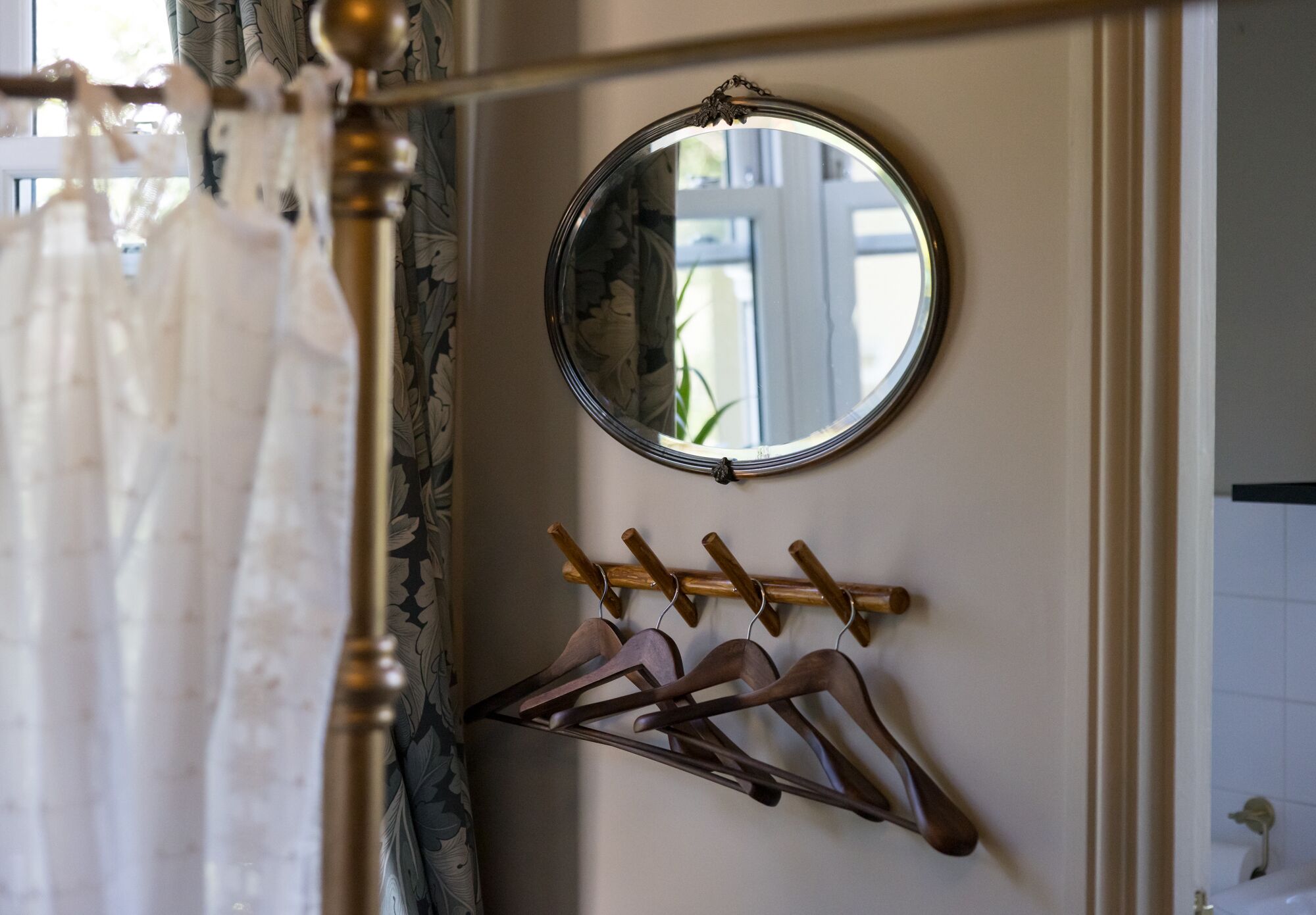 A mirror with a wooden hanger rack below it.