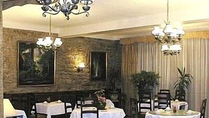 A dining area with tables set for two, stone walls, and chandeliers. - Hôtel de Paris (Poligny)