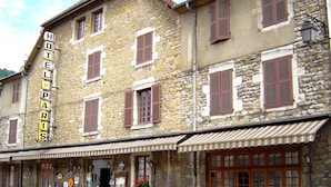 A stone building with a sign reading "HOTEL DE PARIS." It features multiple windows with shutters, a covered entrance, and potted plants outside. - Hôtel de Paris (Poligny)