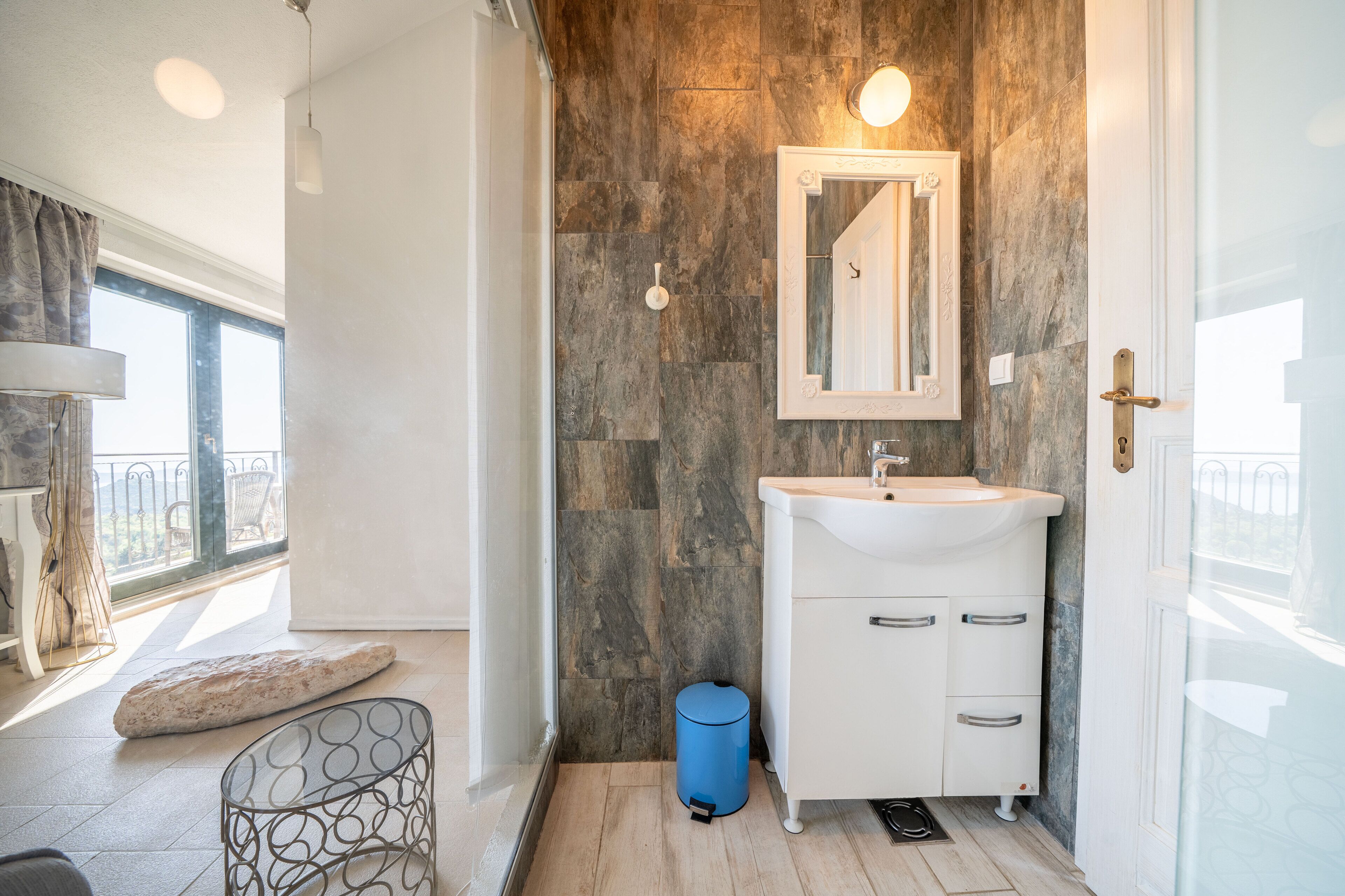 Une salle de bain moderne avec un mur en pierre, un lavabo blanc et un miroir.