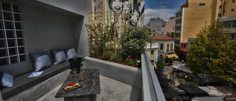 A rooftop terrace with a table, seating, and a view of the cityscape.