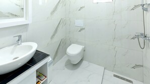 Un baño con lavamanos, inodoro y ducha blancos.