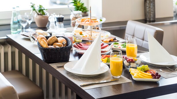 A breakfast buffet with various food items, plates, and glasses of orange juice.