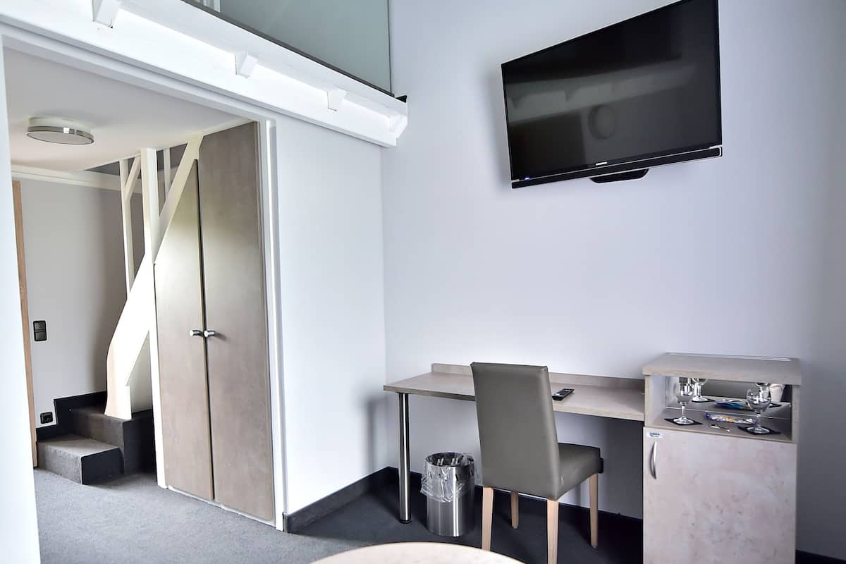 Een moderne kamer met een ronde tafel, een bureau, een stoel, een televisie en een trap.
