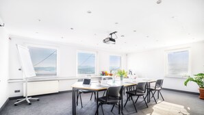 A conference room with a long table, black chairs, a whiteboard, and a projector.