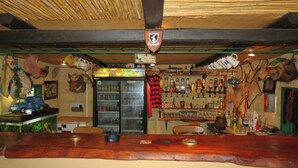 A bar with a wooden counter, various bottles, and a shield-shaped sign above.