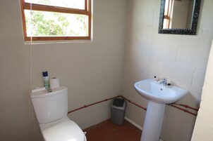 Un baño pequeño con inodoro, lavamanos y ventana.